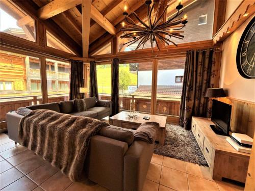 un grand salon avec un canapé et une télévision dans l'établissement Appartement spacieux, 3 pièces + mezzanine, parking, Wifi - FR-1-598-79, aux Gets