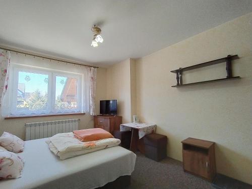 a bedroom with a bed and a tv and a window at U Wacławików in Zakopane