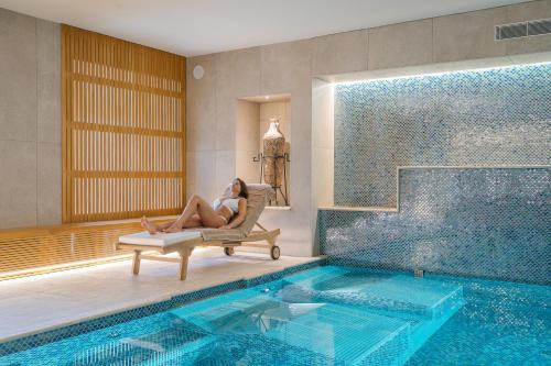 a woman sitting in a chair next to a swimming pool at Hotel Mary in Vico Equense