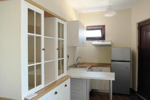 uma cozinha com armários brancos, um lavatório e um frigorífico em Giota's Gasthaus em Zakharo