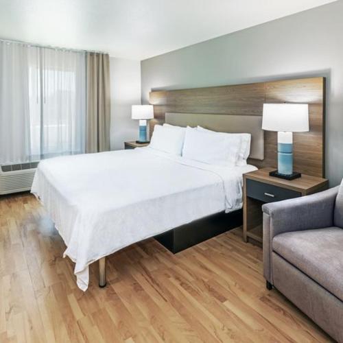 um quarto de hotel com uma cama grande e um sofá em Candlewood Suites - Muskogee, an IHG Hotel em Muskogee