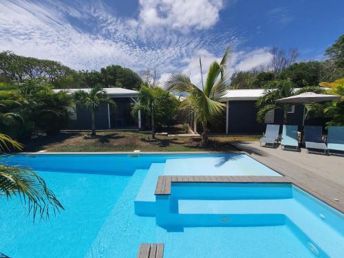 une piscine bleue avec des chaises et une maison dans l'établissement Chez Rustine et Pompette, à Saint-François