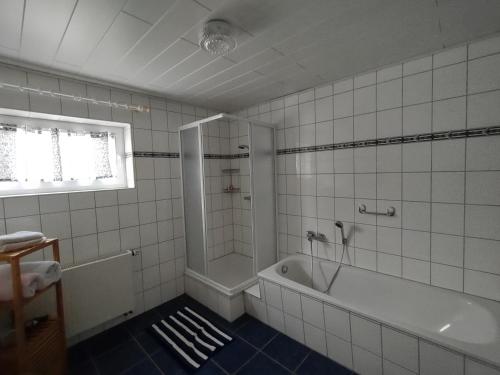 y baño de azulejos blancos con bañera y ducha. en Ferienwohnung Orchidee Eckenhagen, en Reichshof 