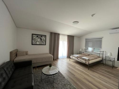 uma sala de estar com um sofá e uma cama em Evita Apartmani Šibovska em Prnjavor