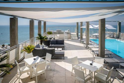 une terrasse avec des tables et des chaises ainsi qu'une piscine dans l'établissement Hotel Marco Polo, à Caorle