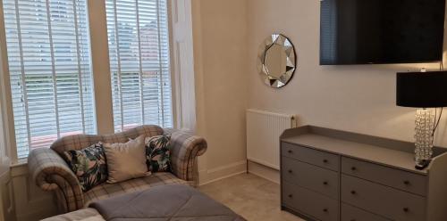 a living room with a chair and a dresser and a mirror at No 9 retreat in Prestwick