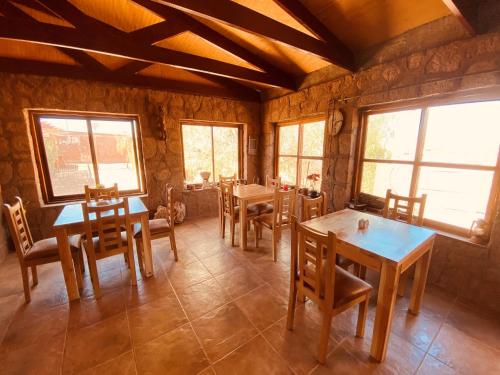 a dining room with tables and chairs and windows at Hostal Katari in San Pedro de Atacama