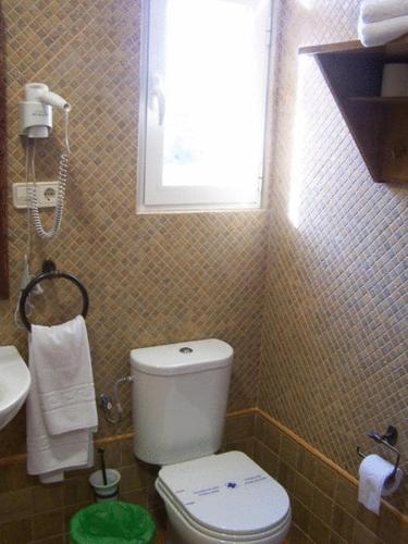 a bathroom with a white toilet and a window at Balneario San Andres in Canena