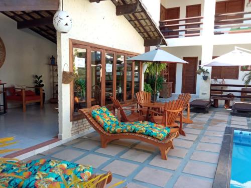 patio z krzesłami i stołem oraz basenem w obiekcie Pousada Vila Morena w mieście Itaúnas