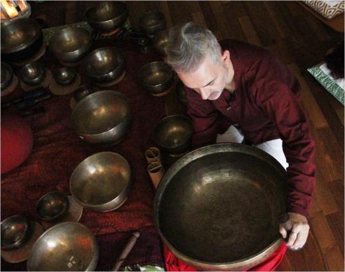 a man is bending over a large metal pot at Boutique B&B and Wellness la Casa dei 5 Elementi in Giubiasco