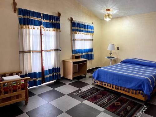 a bedroom with a blue bed and a checkered floor at Casa Taller zapoteca Huella Carmín in Teotitlán del Valle