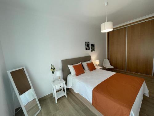 ein Schlafzimmer mit einem Bett mit orangefarbenen Kissen und einem Spiegel in der Unterkunft Alojamento S. Gabriel 1 in Monchique