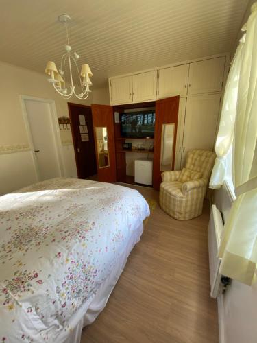 a bedroom with a bed and a chandelier at Pousada Chateau Colinas in Campos do Jordão