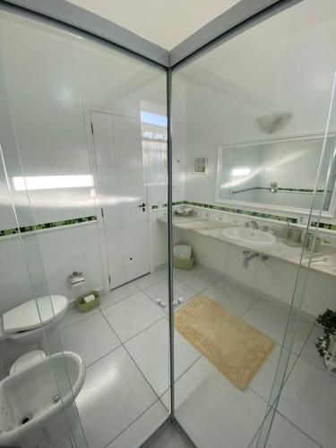 a bathroom with a glass shower and two sinks at Pousada Chateau Colinas in Campos do Jordão