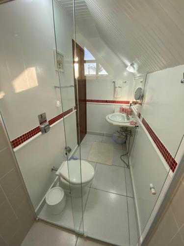 a bathroom with two toilets and a glass shower at Pousada Chateau Colinas in Campos do Jordão