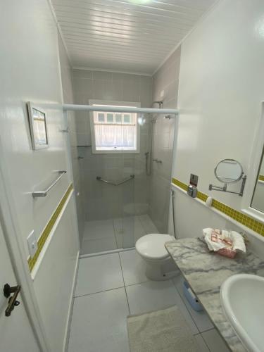 a bathroom with a shower and a toilet and a sink at Pousada Chateau Colinas in Campos do Jordão