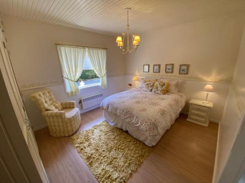 a bedroom with a bed and a chair and a chandelier at Pousada Chateau Colinas in Campos do Jordão