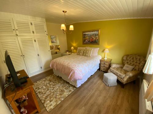 a bedroom with a bed and a chair and a tv at Pousada Chateau Colinas in Campos do Jordão