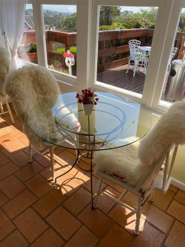 a glass table and chairs in a room with a balcony at Pousada Chateau Colinas in Campos do Jordão