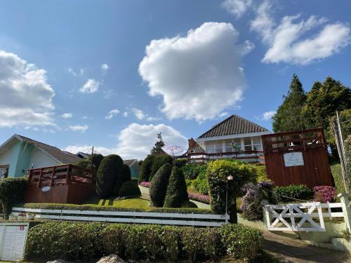 una casa con un jardín con arbustos y árboles en Pousada Chateau Colinas, en Campos do Jordão