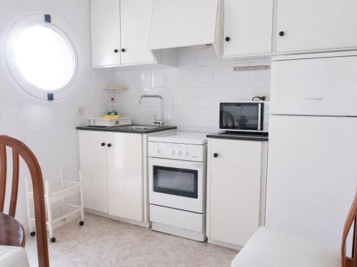 eine Küche mit weißen Schränken und einem weißen Kühlschrank in der Unterkunft Agusti Hostal in Sant Carles de la Ràpita