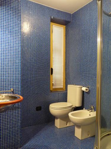 a blue tiled bathroom with a toilet and a sink at Apartment Lido in Gozzano