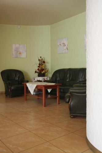 a living room with two leather couches and a table at Hotel Przylesie in Sierosław