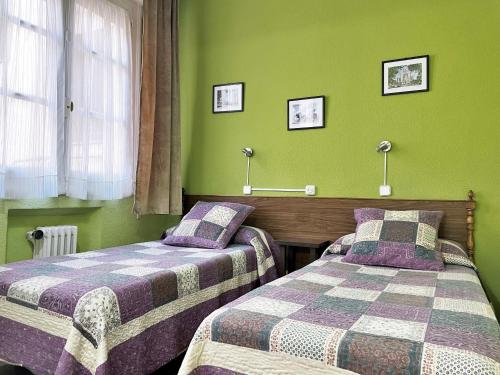 2 camas en una habitación con paredes verdes en Hostal San Martin, en Madrid