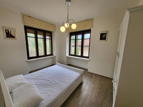 Un dormitorio con una cama blanca y dos ventanas. en Big appartement - 9 guests - Air Conditionning and Courtyard, en Bussoleno