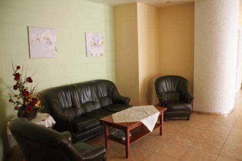 a living room with two leather couches and a coffee table at Hotel Przylesie in Sierosław
