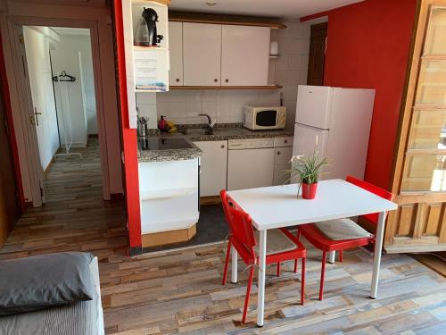 a small kitchen with a white table and red chairs at Viva León in León
