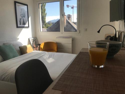 a glass of orange juice sitting on a table in a bedroom at Brooklyn - Studio moderne à 2 pas du tram A in Grenoble