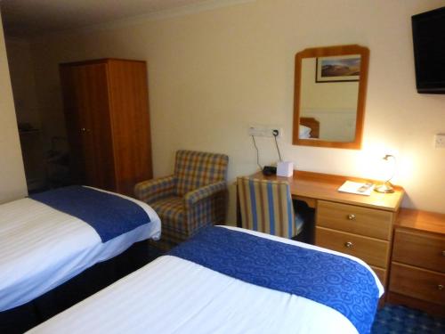 a hotel room with two beds and a desk and a chair at Norseman Hotel in Wick