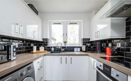 una cocina con armarios blancos y fregadero en Alltan at Culloden en Culloden