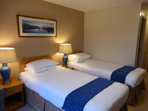 two beds in a hotel room with two lamps at Norseman Hotel in Wick
