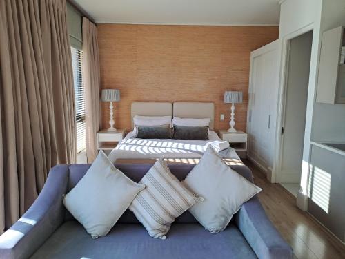1 dormitorio con 1 cama y 1 sofá con almohadas en The Rex Studio Apartment, en Knysna