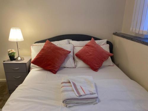a bed with red and white pillows and a lamp at Luxury Apartment in Woolwich Arsenal in Woolwich