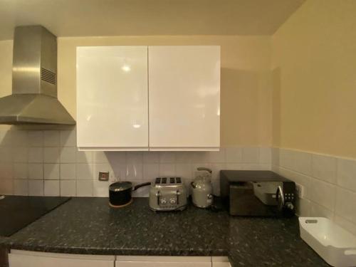 a kitchen with white cabinets and a black counter top at Luxury Apartment in Woolwich Arsenal in Woolwich