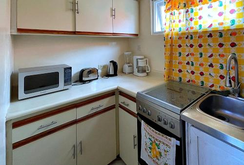 a small kitchen with a microwave and a sink at Oceanfront Condo w/ FREE Parking + High Speed Wifi in Negril