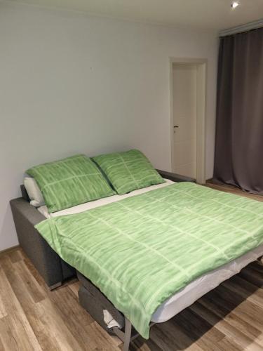 a bedroom with a bed with a green comforter at Maria Apartment in Wolfsburg