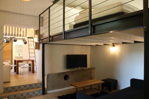 a living room with a couch and a tv in a loft at Mas Thomasine Séjour Romantique au calme in Peillon