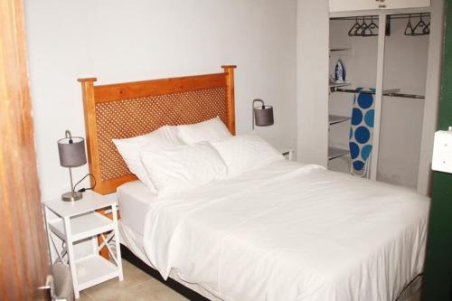 um quarto com uma cama branca e uma cabeceira em madeira em Adorable 1.5 -Bedroom flatlet in Germiston em Germiston