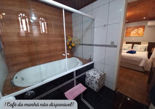 a bathroom with a bath tub and a bedroom at Hospedagem Alternativa Família Martins in Urubici