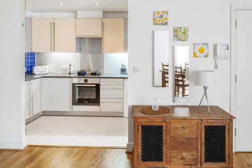 a kitchen with white cabinets and a wooden table at Comfortable and Bright Apartment in Tower Bridge in London