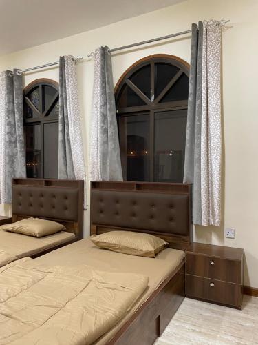 2 letti in una camera con 2 finestre di Mutrah Lux Apartment a Mascate