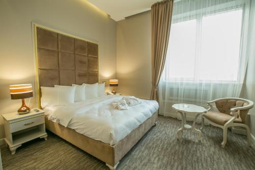 a hotel room with a bed and a chair and a window at Grand Sapphire Hotel in Almaty