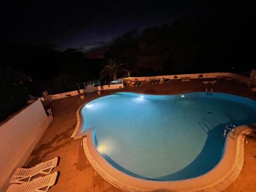 a swimming pool at night with chairs around it at FLAT Surrounded by Nature WIFI & Pool & beach Nearby in Son Parc