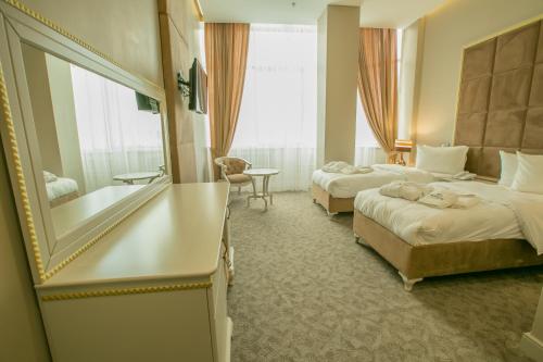 a hotel room with two beds and a mirror at Grand Sapphire Hotel in Almaty