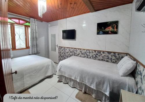 a hotel room with two beds and a tv at Hospedagem Alternativa Família Martins in Urubici