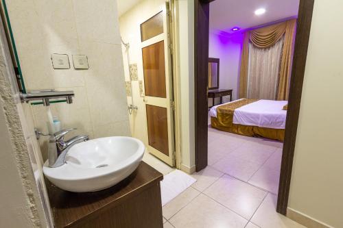 uma casa de banho com um lavatório e um quarto com uma cama em النايفة للشقق المفروشة em Al Khobar